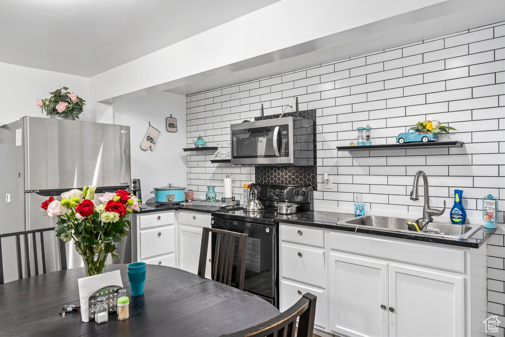 Kitchen with appliances with stainless steel finishes, white cabinetry, sink, and tasteful backsplash