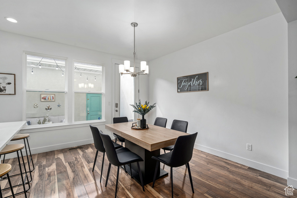 Dining area with an inviting chandelier and dark hardwood / wood-style flooring