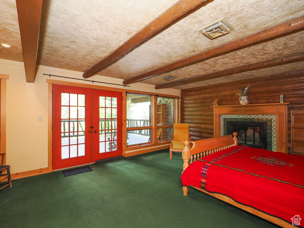 Bedroom with beamed ceiling, french doors, rustic walls, and a tiled fireplace