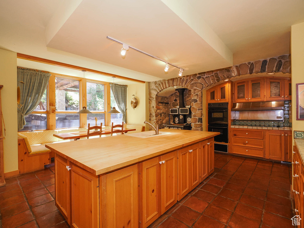 Kitchen featuring a wood stove, wood counters, dark tile flooring, sink, and double oven