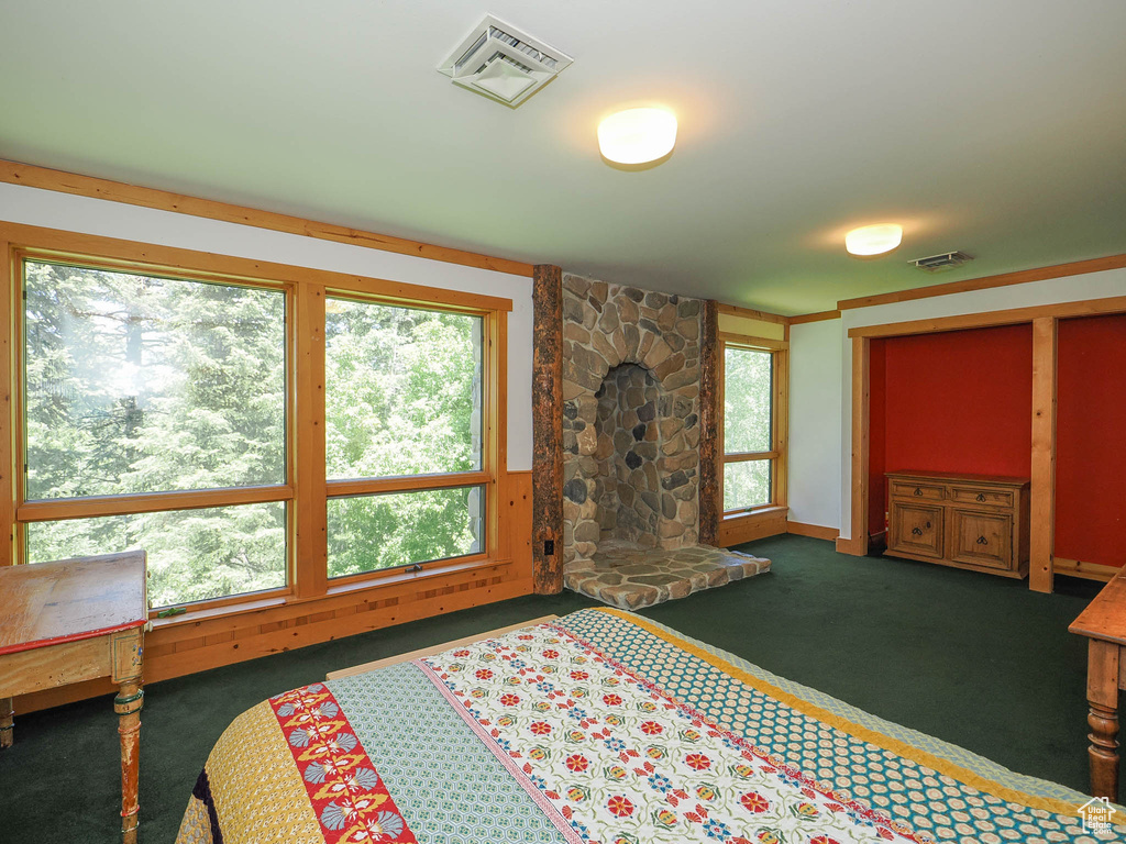 Bedroom with dark carpet and a stone fireplace