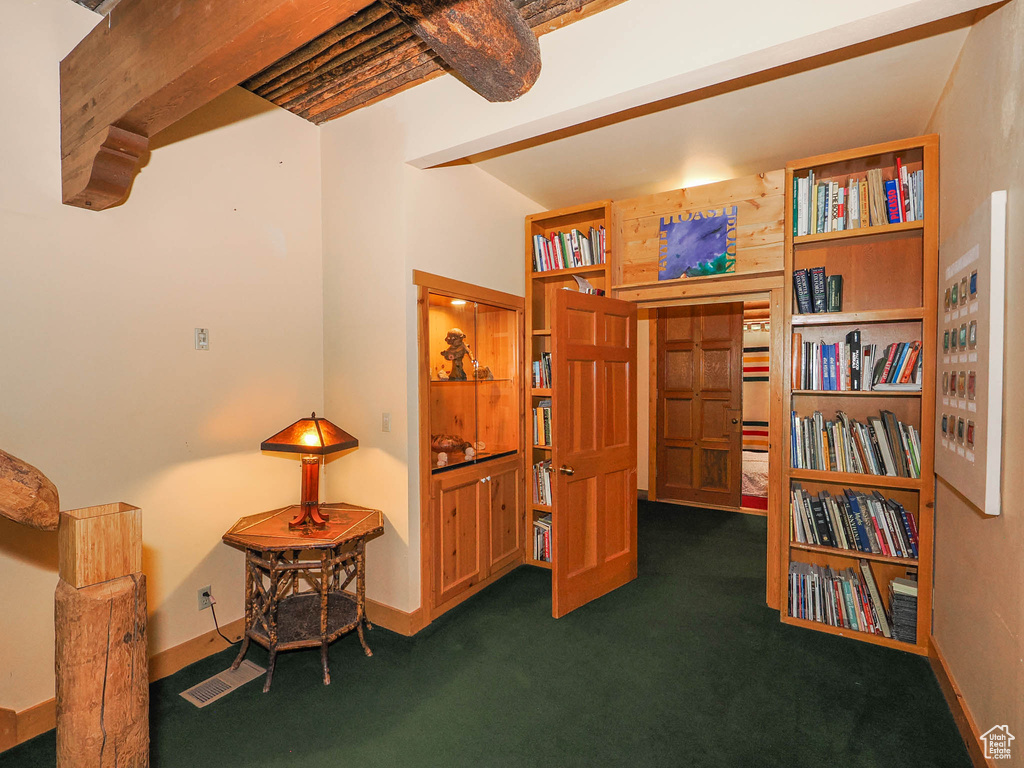 Sitting room with beamed ceiling and dark colored carpet