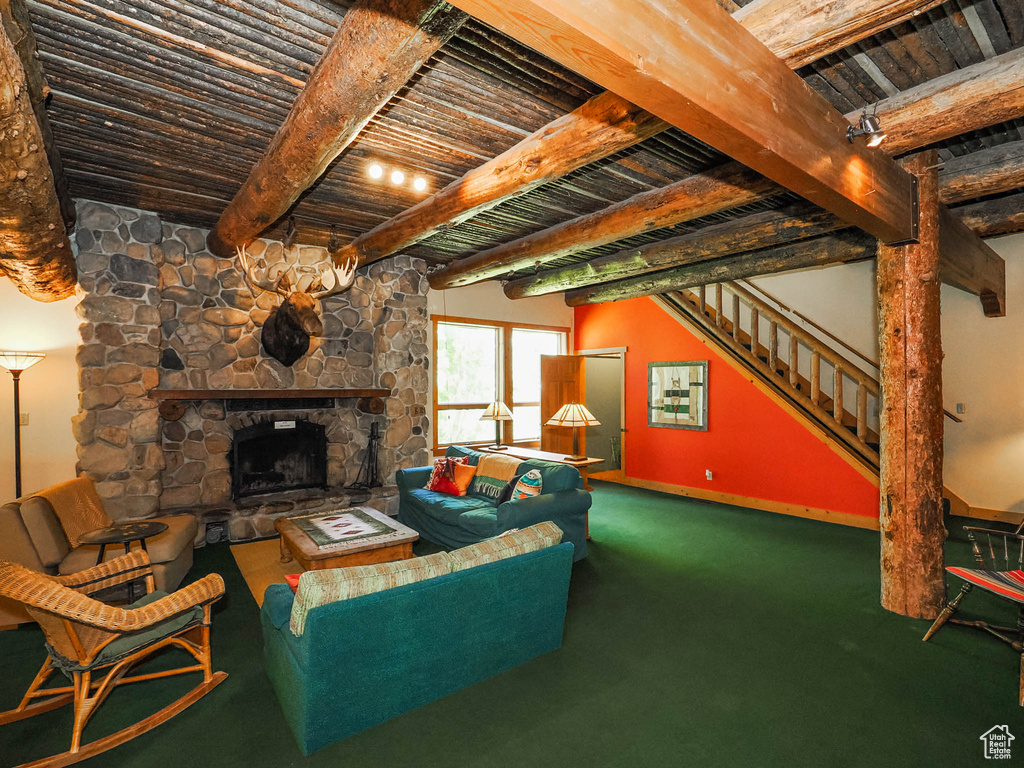 Living room with beamed ceiling, carpet floors, a fireplace, and wooden ceiling