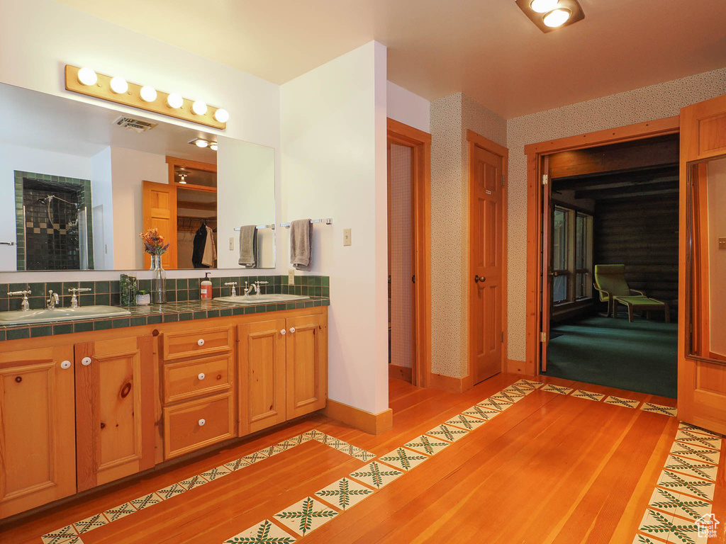 Bathroom with hardwood / wood-style flooring, double sink, and vanity with extensive cabinet space