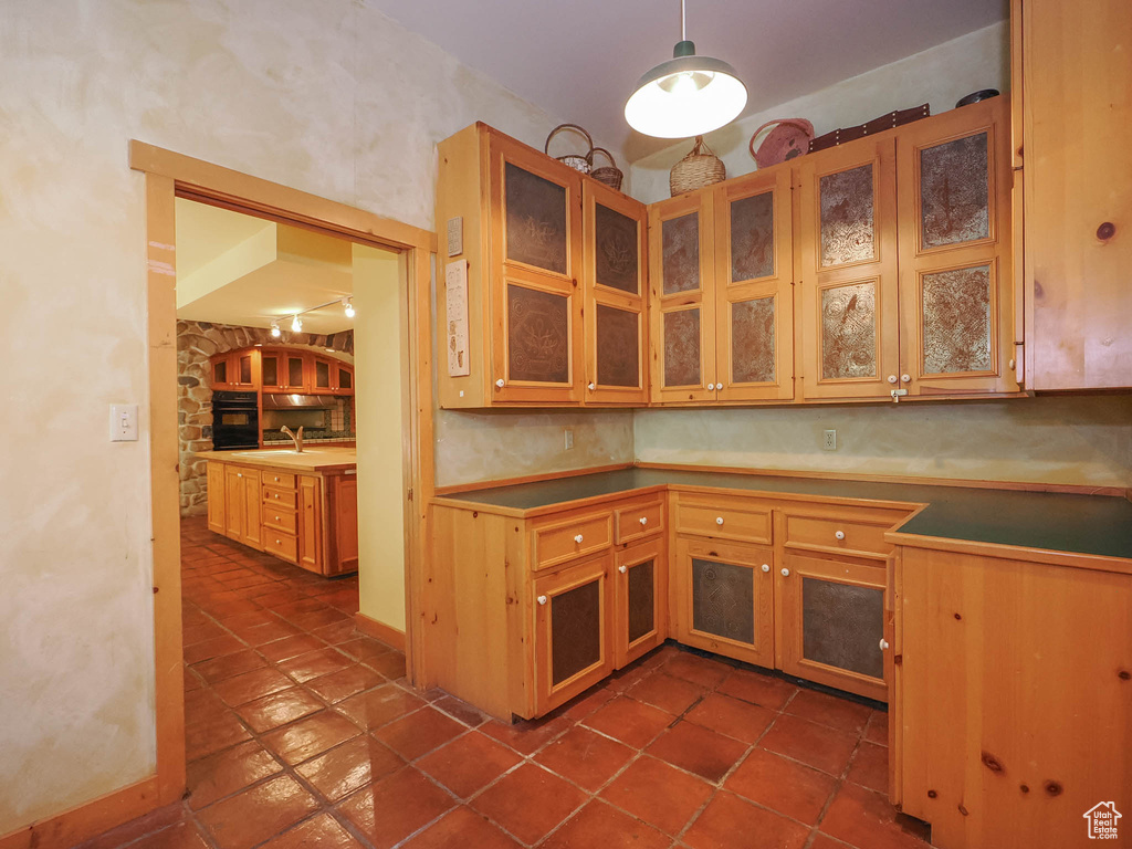 Kitchen with sink, hanging light fixtures, black oven, and dark tile floors