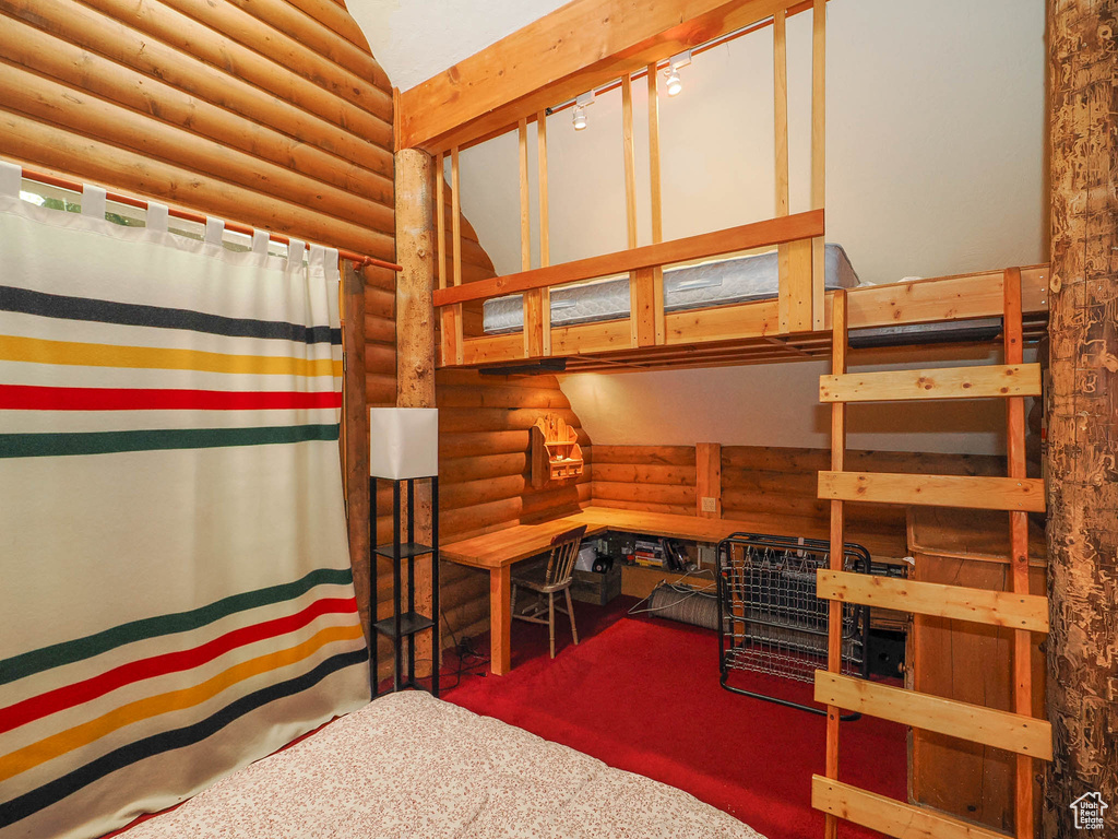 Bedroom featuring carpet, lofted ceiling, log walls, and track lighting