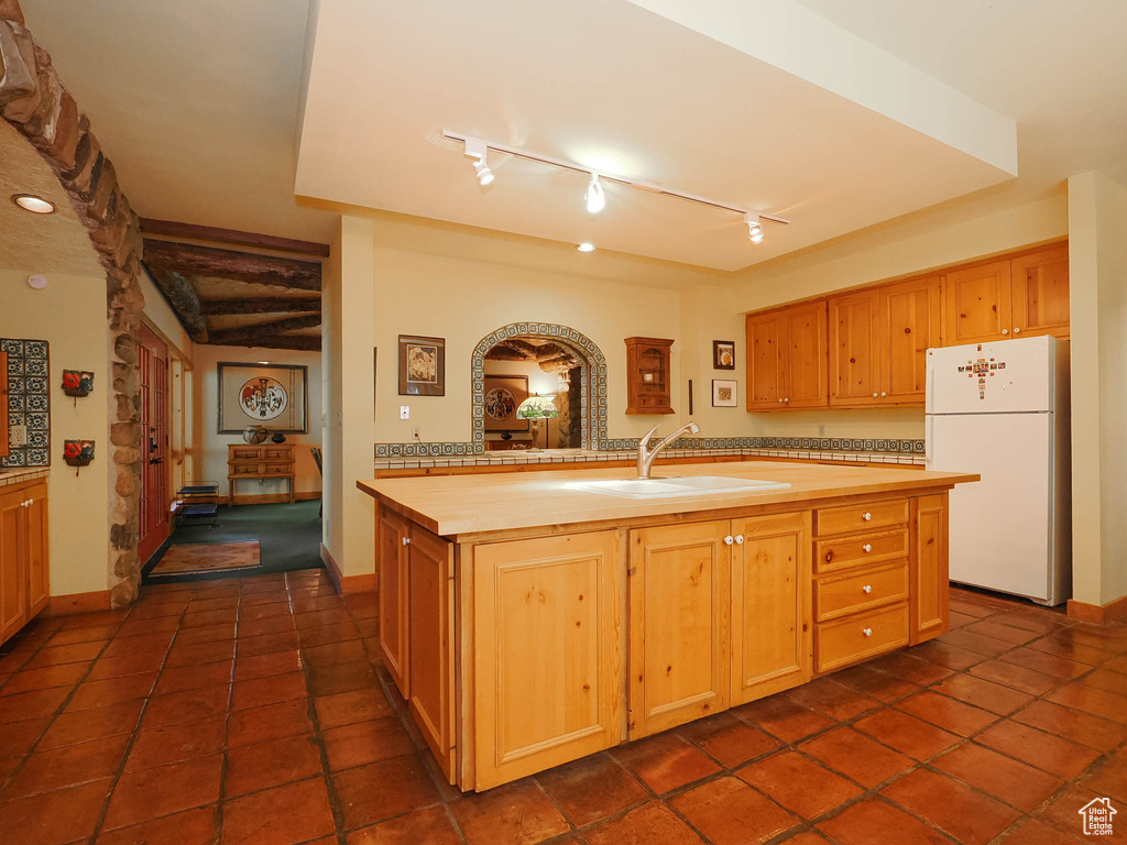 Kitchen with dark tile floors, sink, and white refrigerator