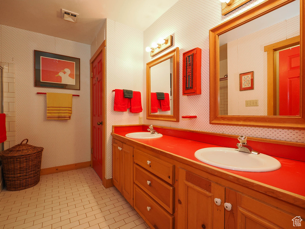 Bathroom featuring dual bowl vanity and tile floors