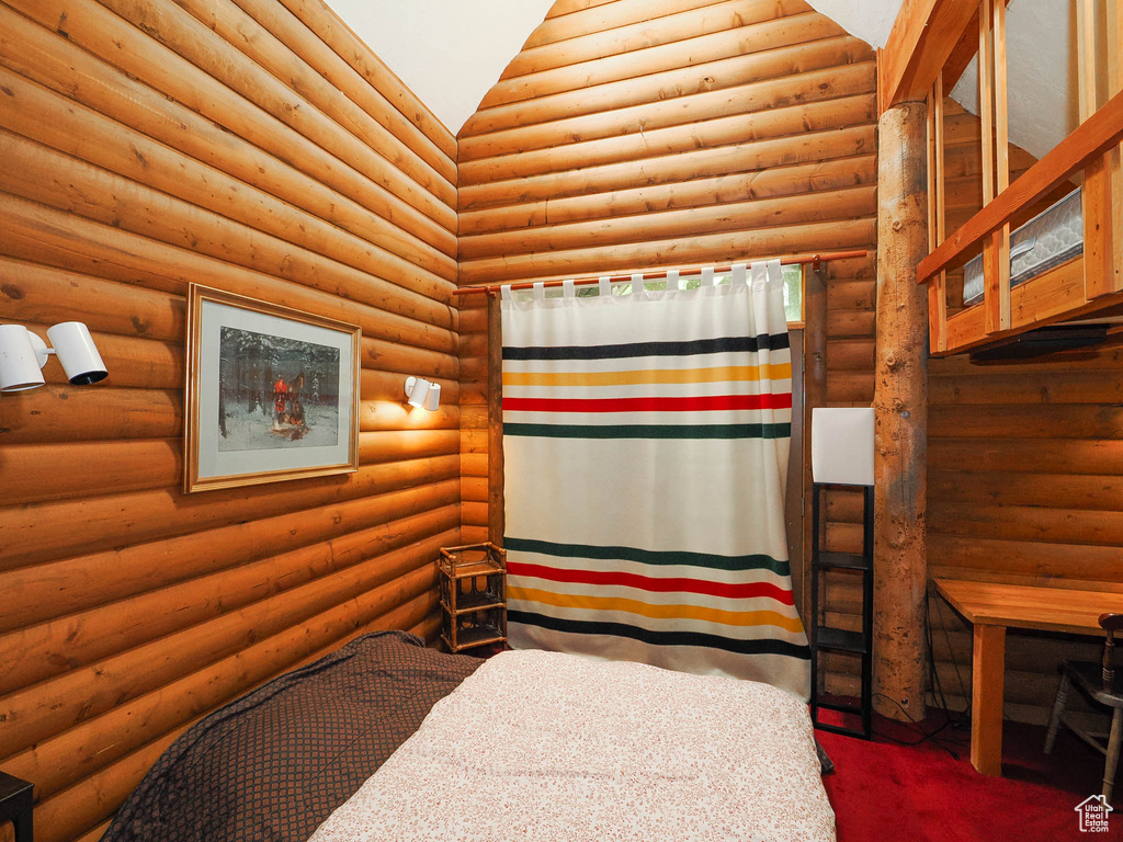 Bedroom with rustic walls and carpet floors