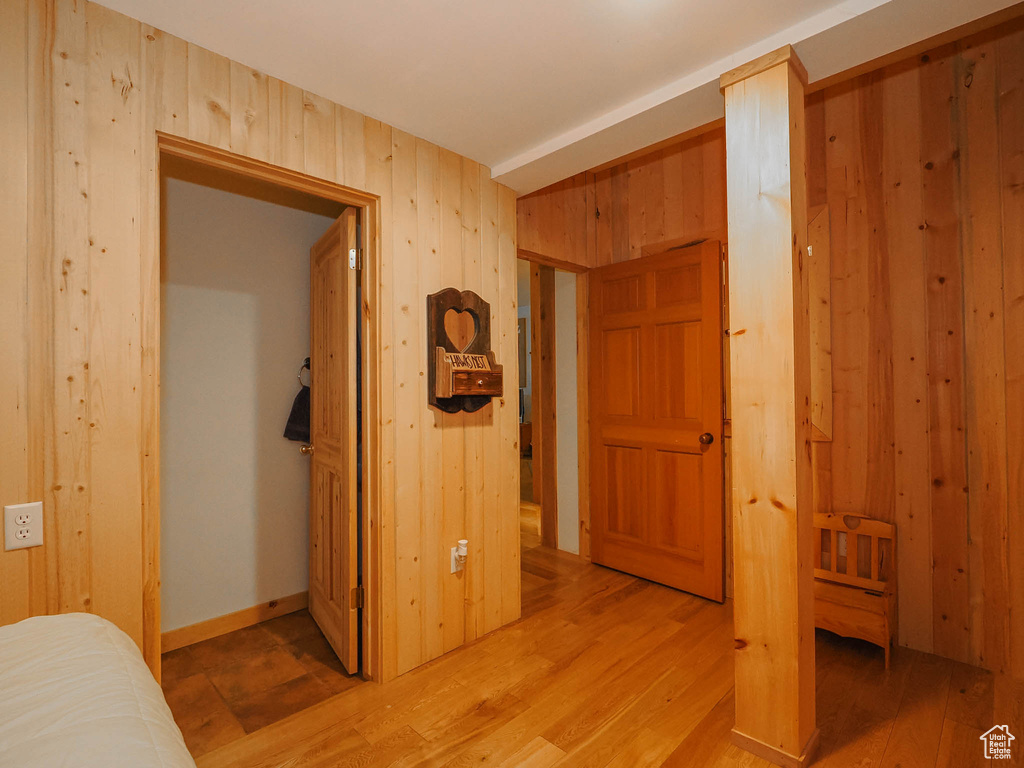 Bedroom with wooden walls and light wood-type flooring