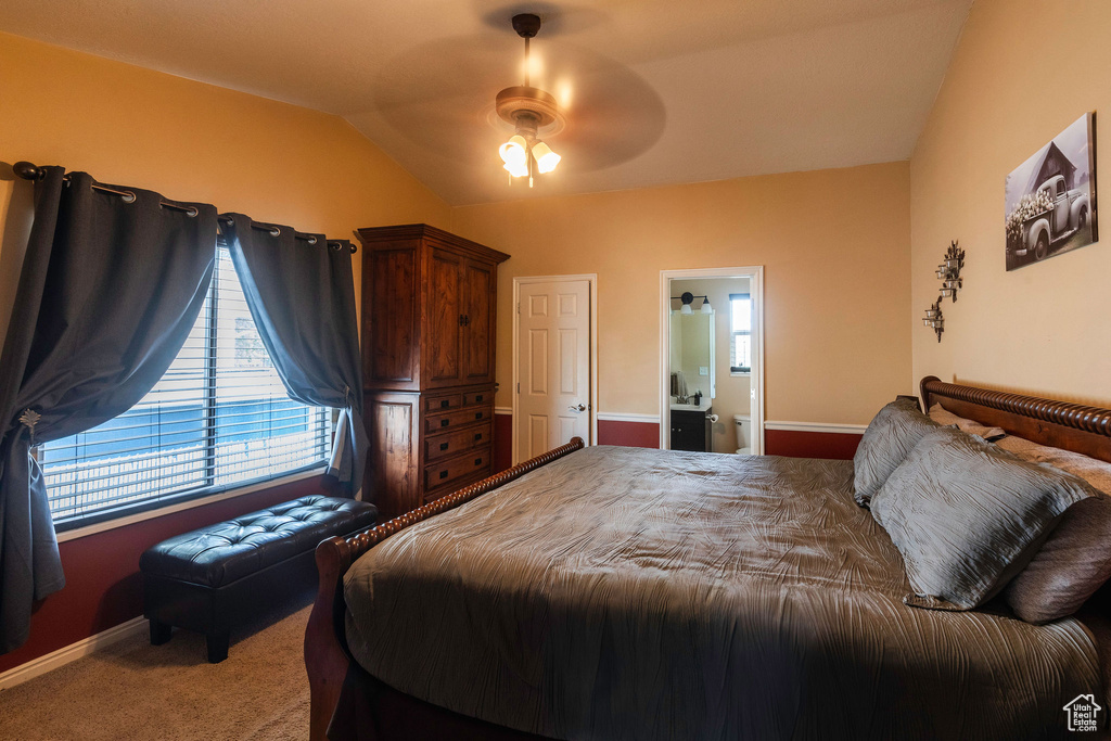 Bedroom with ensuite bathroom, carpet, ceiling fan, and vaulted ceiling