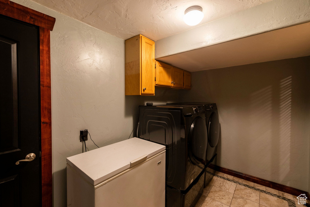 Laundry room featuring cabinets, independent washer and dryer, and light tile floors