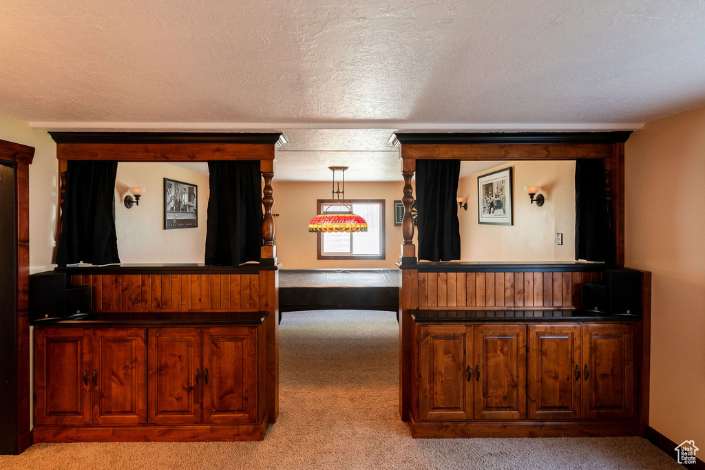 Interior space featuring a textured ceiling, carpet flooring, and pendant lighting