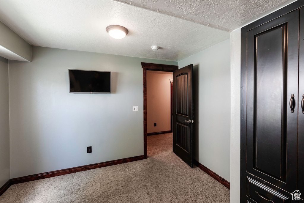 Unfurnished bedroom with light carpet and a textured ceiling