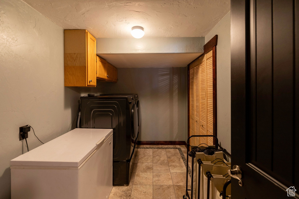 Laundry room with electric dryer hookup, cabinets, light tile floors, and washing machine and clothes dryer