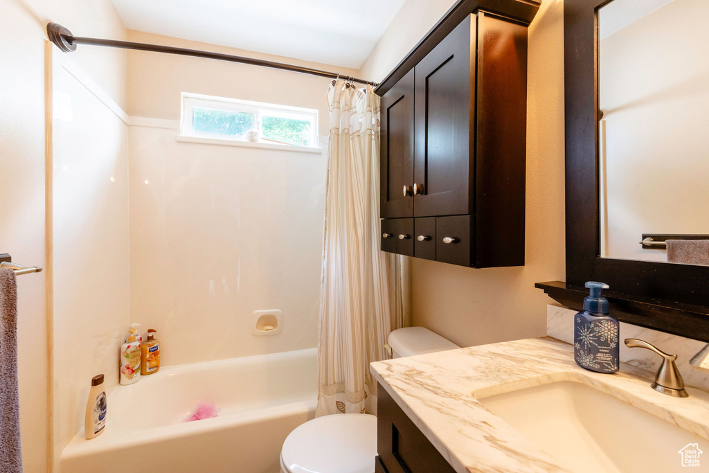 Full bathroom with shower / bathtub combination with curtain, vanity with extensive cabinet space, and toilet