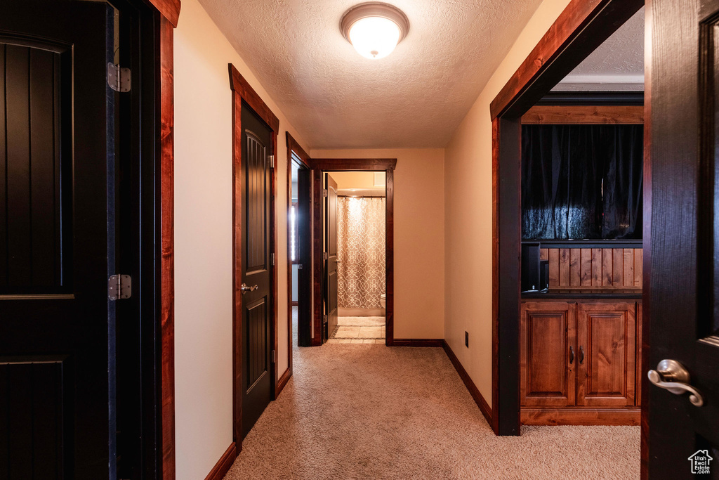 Hall featuring a textured ceiling and light colored carpet