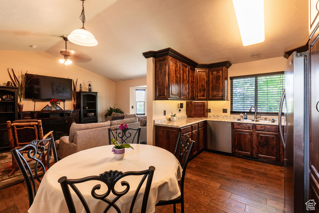 Kitchen with dark wood-type flooring, appliances with stainless steel finishes, dark brown cabinets, ceiling fan, and vaulted ceiling