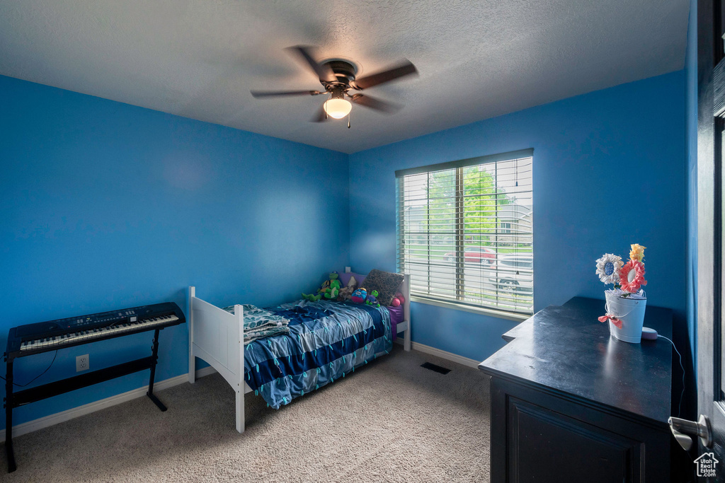 Carpeted bedroom with ceiling fan and a textured ceiling