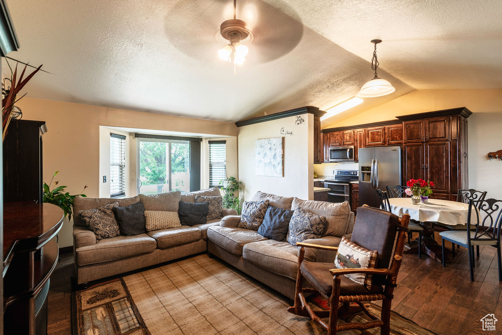 Living room featuring ceiling fan, vaulted ceiling, a textured ceiling, and wood-type flooring