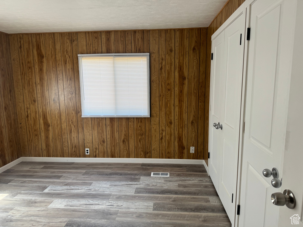 Unfurnished room featuring hardwood / wood-style flooring and wooden walls