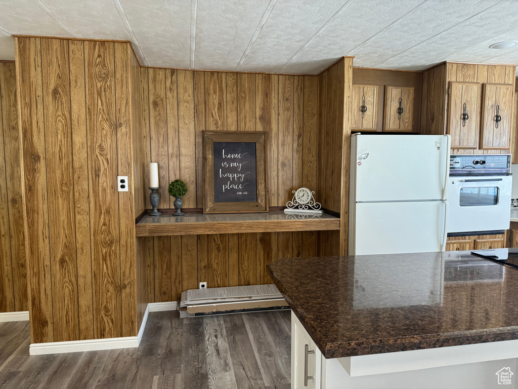 Kitchen featuring wooden walls, white appliances, and dark wood-type flooring