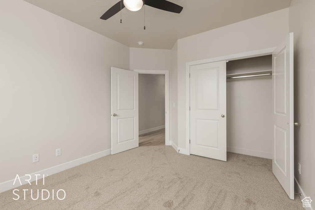 Unfurnished bedroom featuring ceiling fan, a closet, and light colored carpet