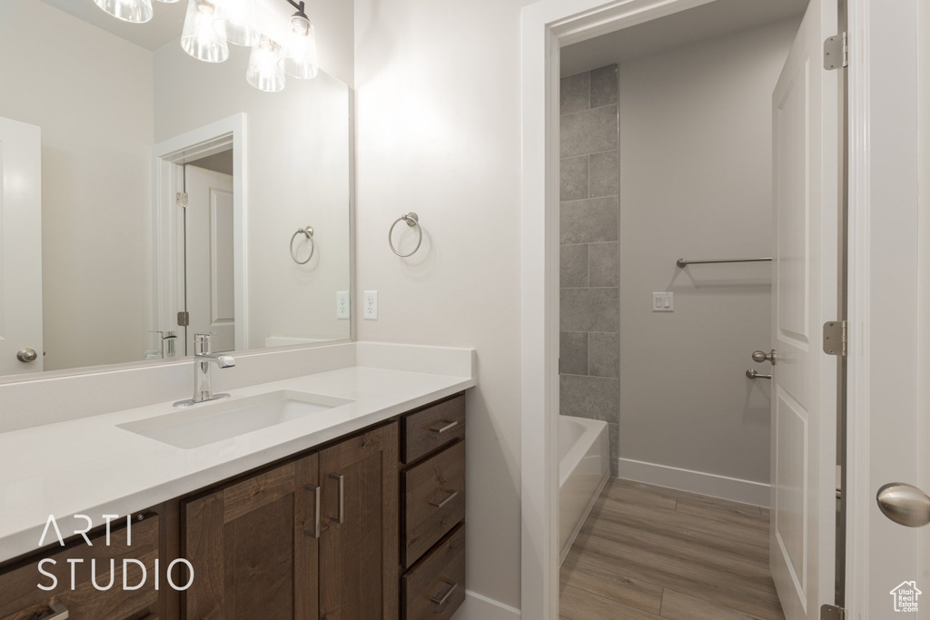 Bathroom with tiled shower / bath, vanity, and hardwood / wood-style flooring