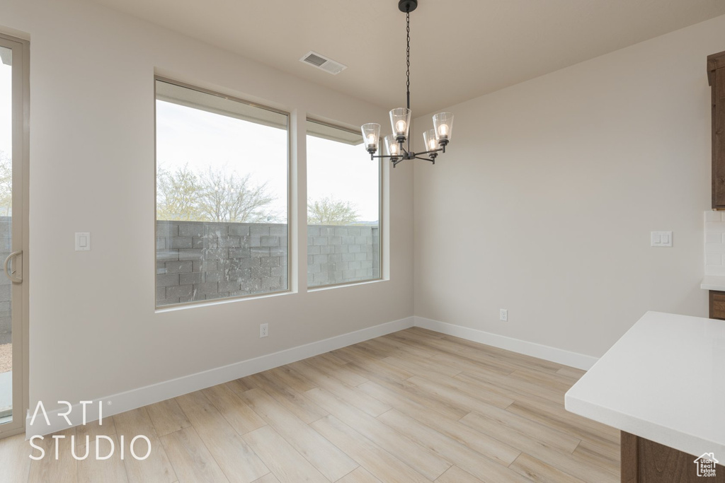 Unfurnished dining area featuring a notable chandelier and light hardwood / wood-style flooring