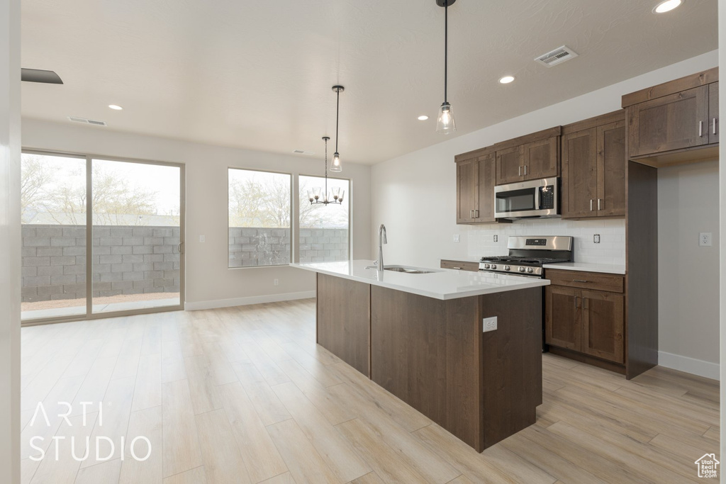 Kitchen featuring an island with sink, sink, light hardwood / wood-style floors, and appliances with stainless steel finishes