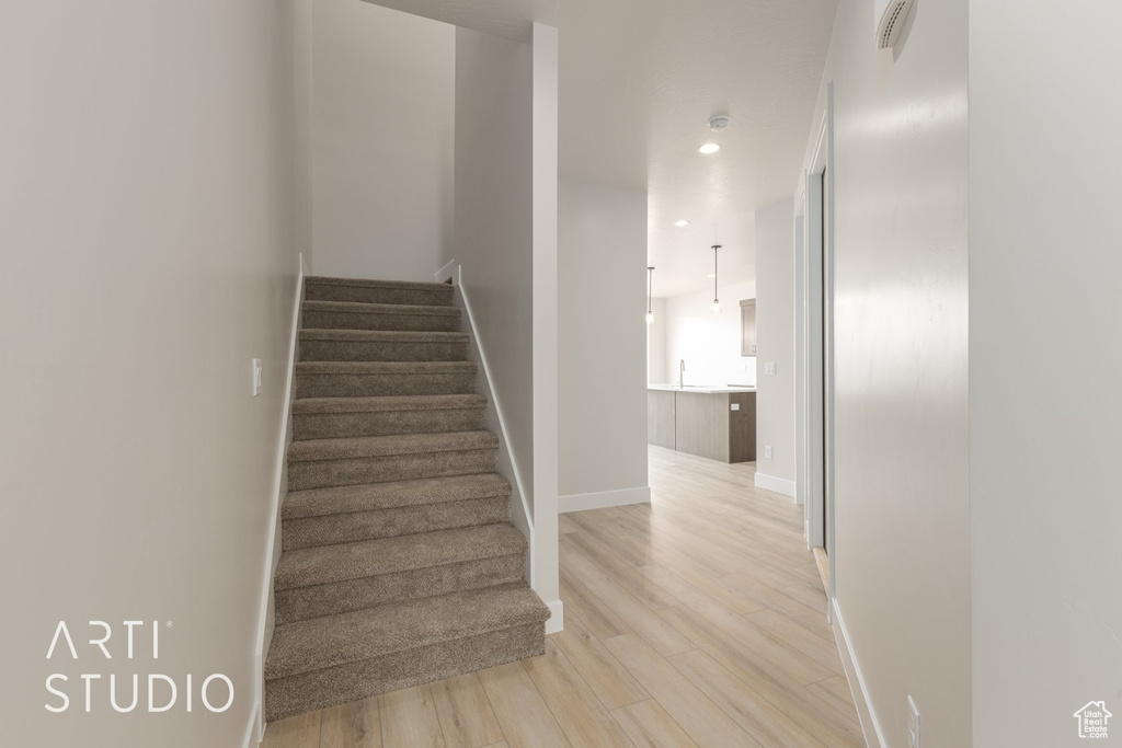 Stairway with light hardwood / wood-style flooring