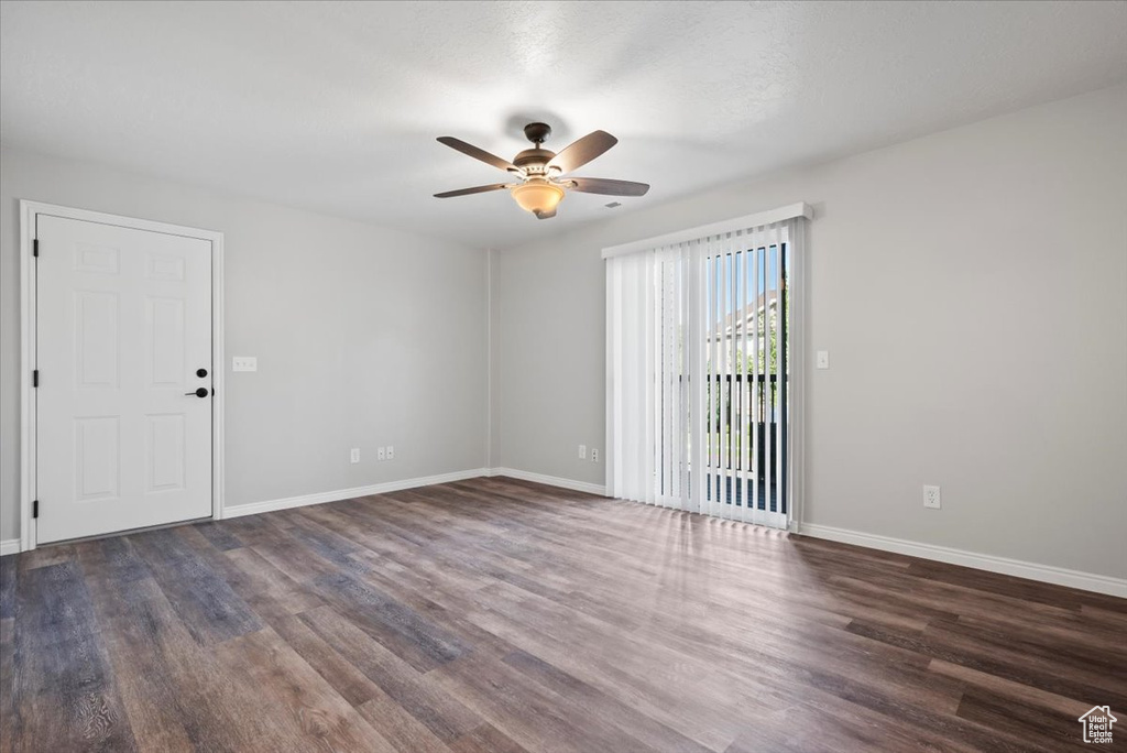 Empty room featuring ceiling fan and dark hardwood / wood-style flooring