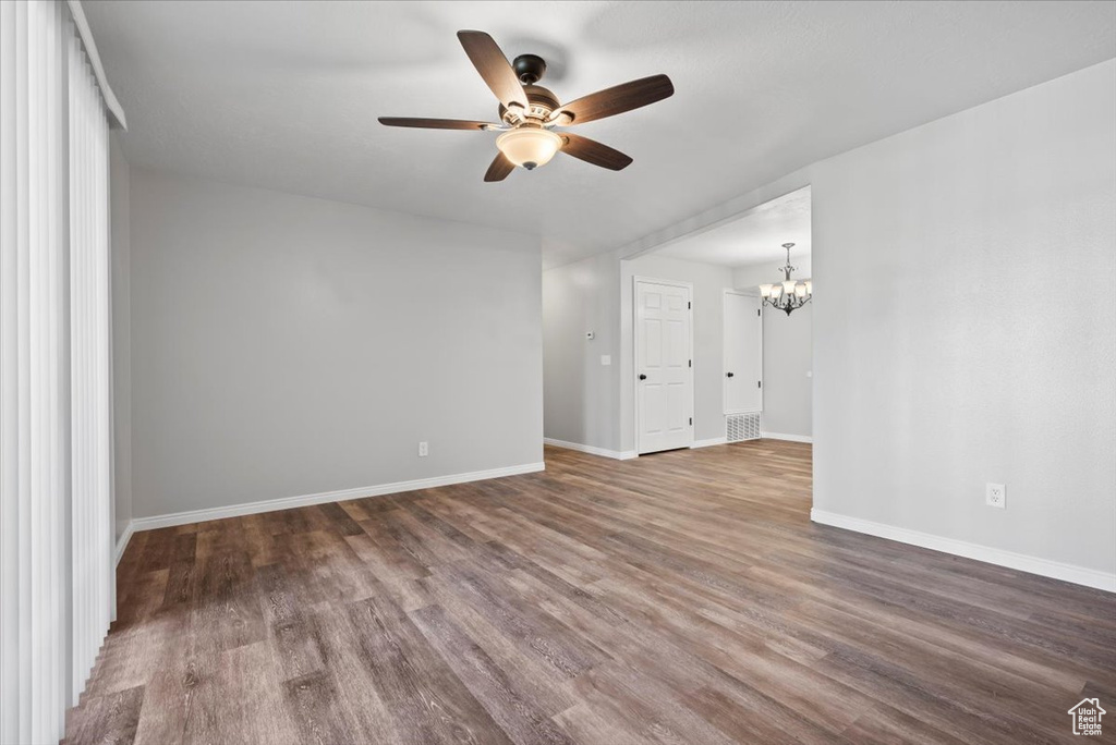 Spare room with wood-type flooring and ceiling fan with notable chandelier