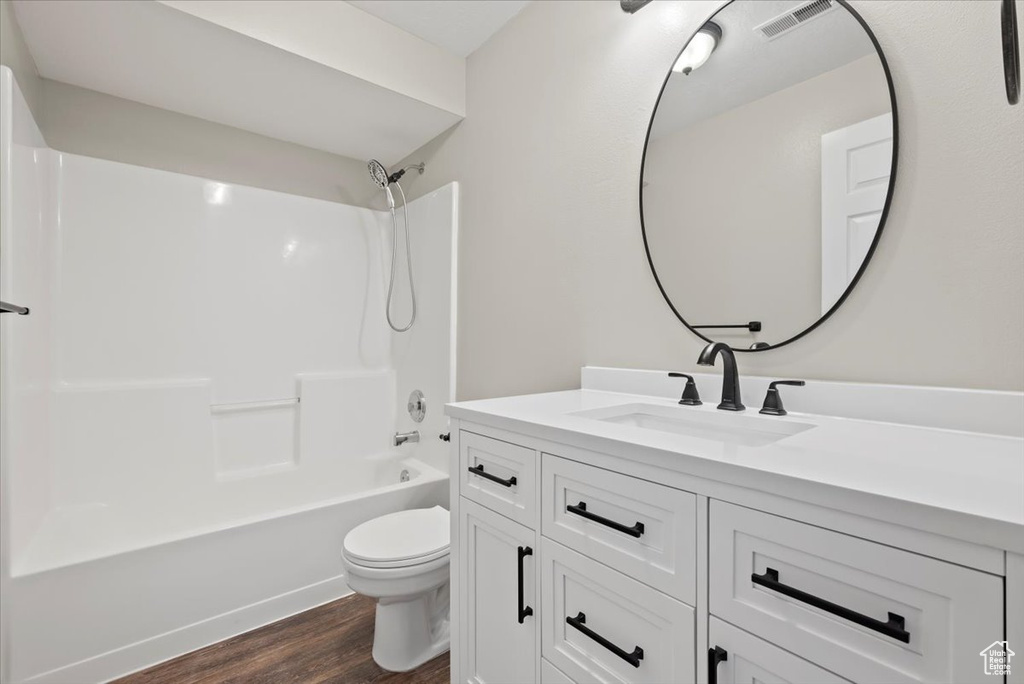 Full bathroom with hardwood / wood-style flooring, shower / washtub combination, large vanity, and toilet