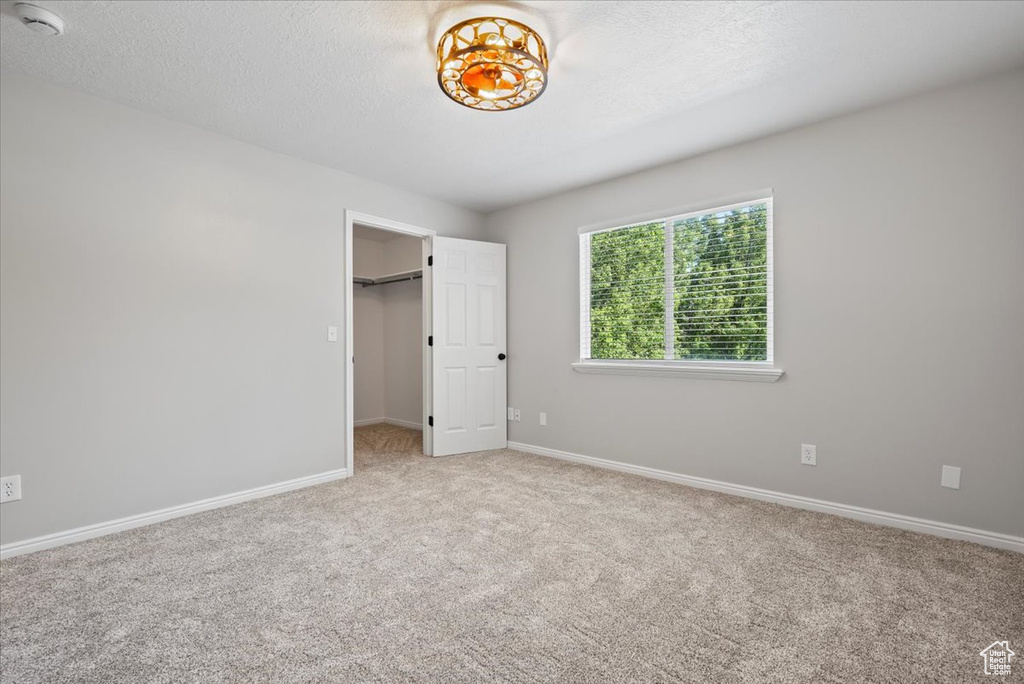 Unfurnished bedroom with carpet and a walk in closet