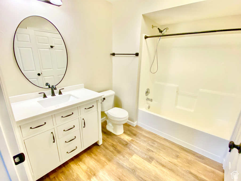 Full bathroom featuring wood-type flooring, shower / washtub combination, vanity, and toilet