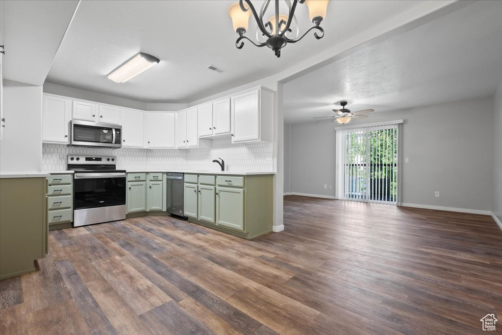 Kitchen with ceiling fan with notable chandelier, dark hardwood / wood-style flooring, tasteful backsplash, and appliances with stainless steel finishes