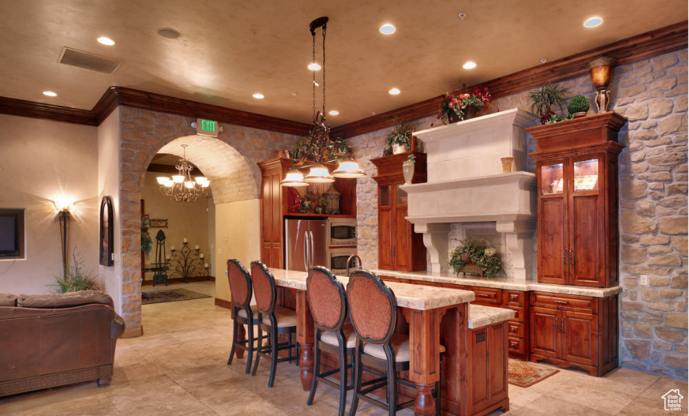 Bar featuring a notable chandelier, hanging light fixtures, light tile floors, and stainless steel appliances