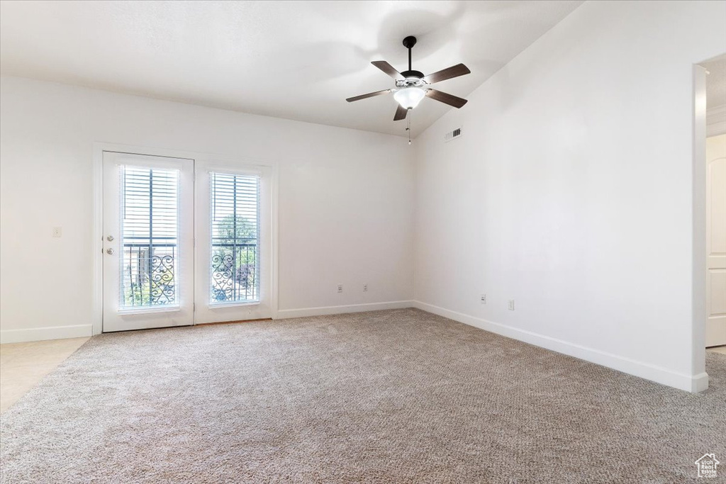 Carpeted spare room featuring vaulted ceiling and ceiling fan