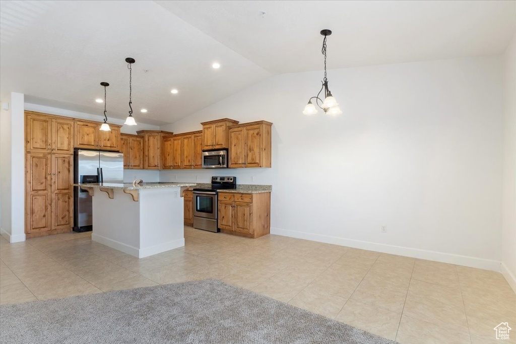 Kitchen with hanging light fixtures, a center island with sink, stainless steel appliances, a breakfast bar area, and light tile floors