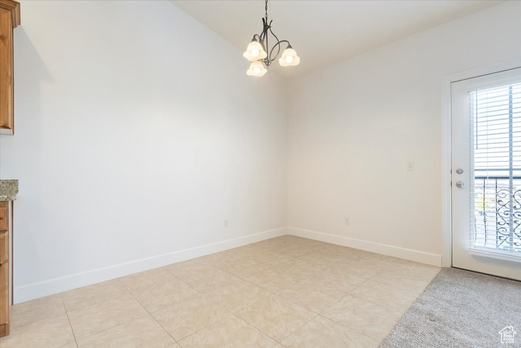 Unfurnished room with a chandelier and light tile flooring