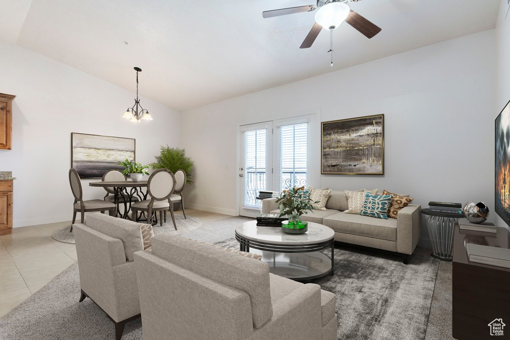 Tiled living room featuring lofted ceiling and ceiling fan with notable chandelier