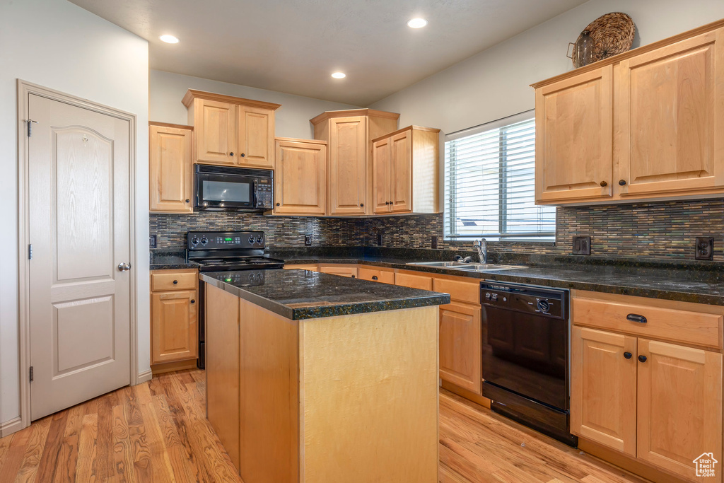 Kitchen featuring light hardwood / wood-style floors, a kitchen island, black appliances, and backsplash