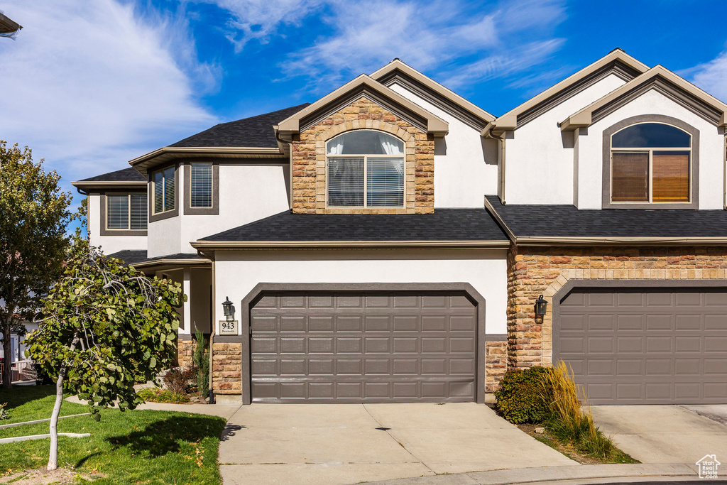 Multi unit property featuring a front lawn and a garage