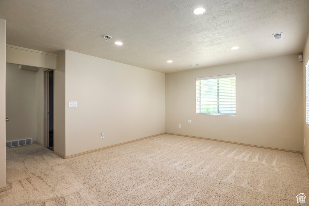 Unfurnished room featuring a textured ceiling and light colored carpet