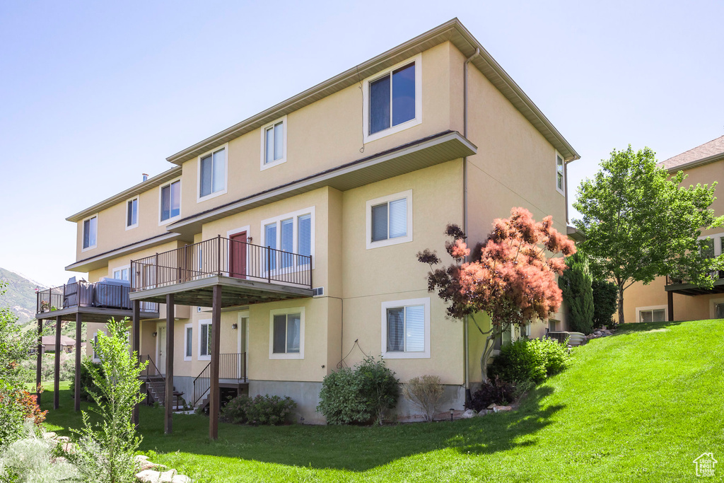 Back of property with a balcony and a lawn