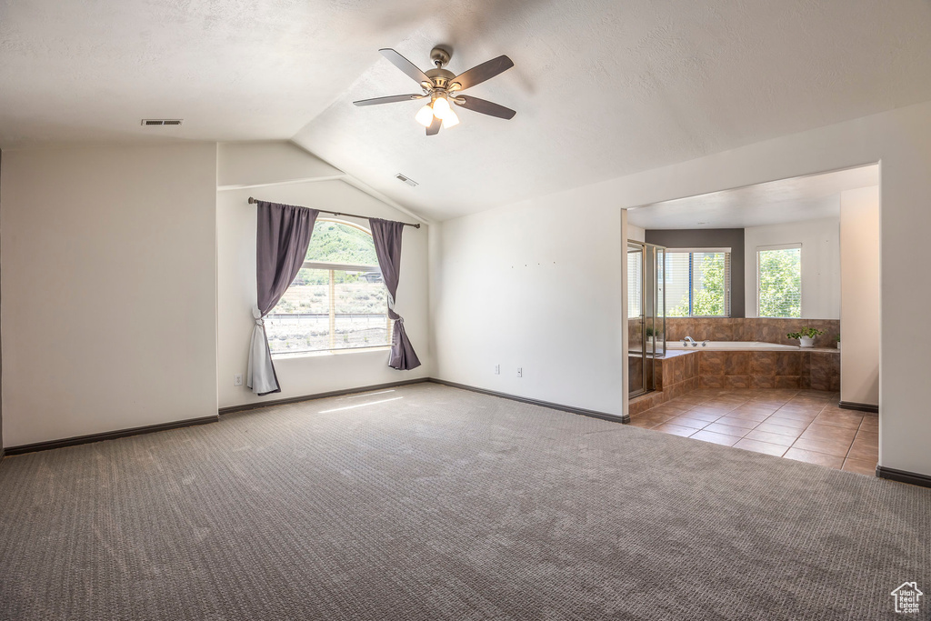 Carpeted empty room featuring ceiling fan and lofted ceiling