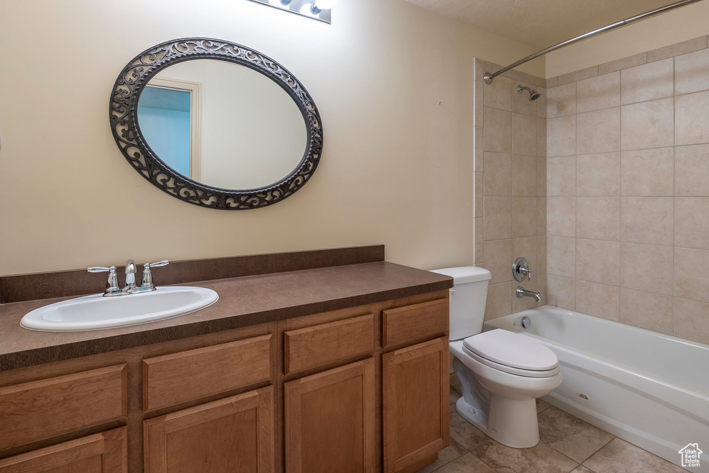 Full bathroom featuring tile flooring, vanity, toilet, and tiled shower / bath combo