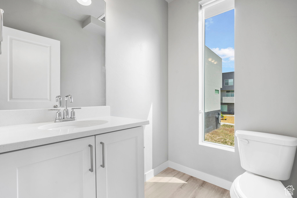 Bathroom with wood-type flooring, oversized vanity, and toilet