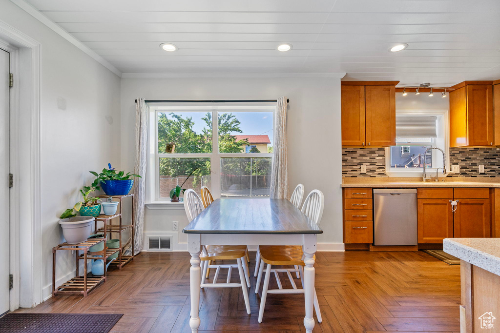 Kitchen featuring crown molding, light parquet floors, dishwasher, backsplash, and sink